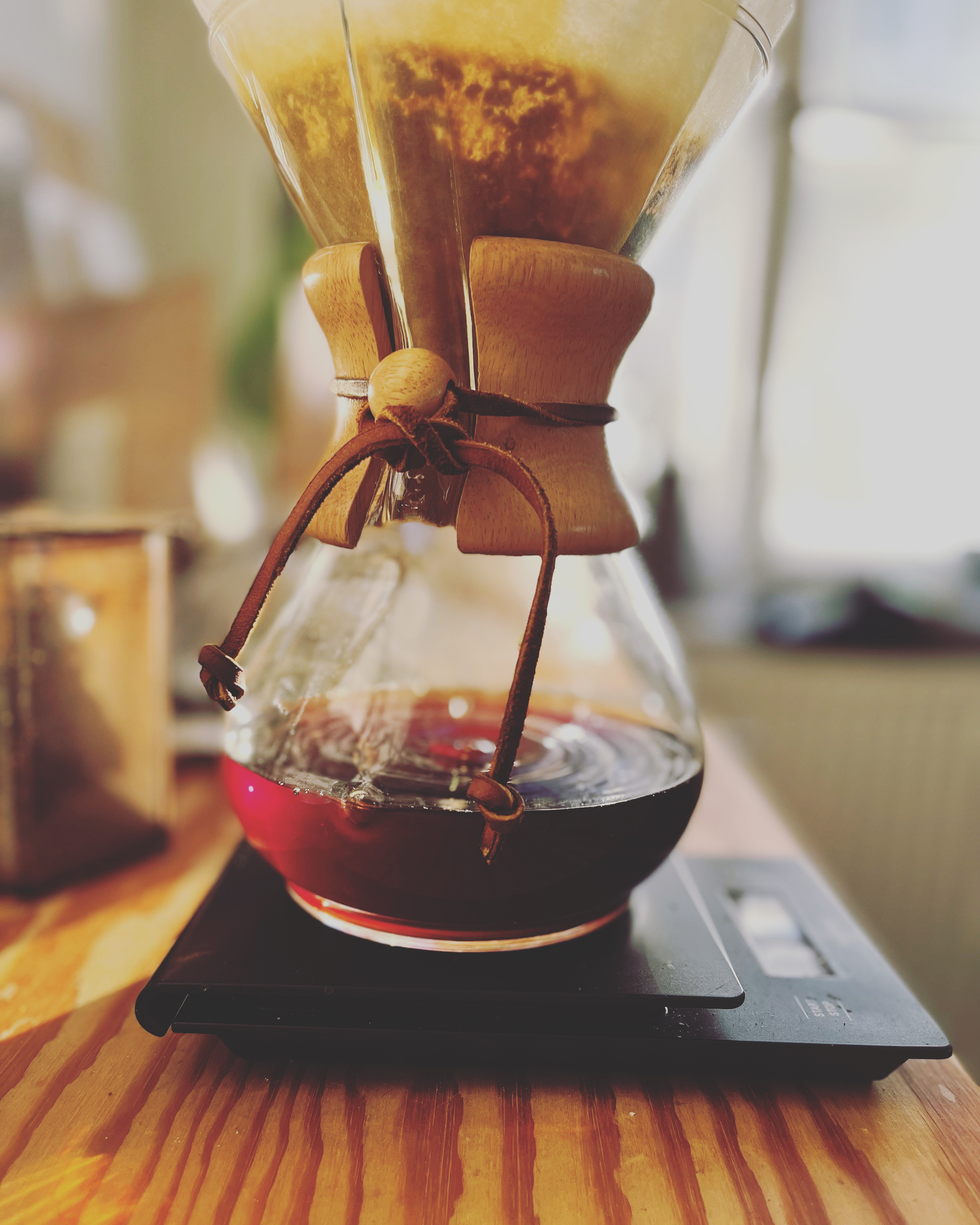 Chemex coffeemaker filled with coffee on a wooden countertop